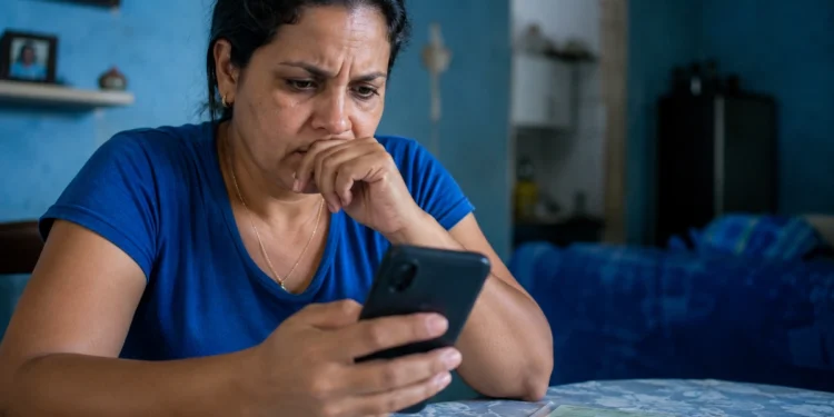 Mulher consulta o celular com expressão de preocupação, representando o possível golpe envolvendo o falso Auxílio Reconstrução de R$ 1.050.