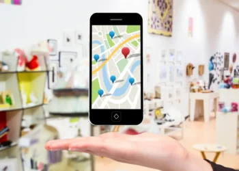Celular com mapa digital e marcadores de localização sobre a mão de uma pessoa.