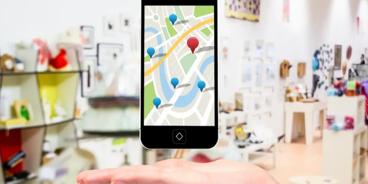 Celular com mapa digital e marcadores de localização sobre a mão de uma pessoa.
