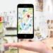Celular com mapa digital e marcadores de localização sobre a mão de uma pessoa.