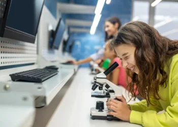 Estudante realiza atividade em laboratório universitário com microscópio durante aula prática de graduação.