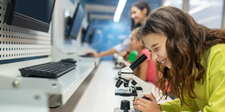 Estudante realiza atividade em laboratório universitário com microscópio durante aula prática de graduação.