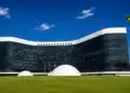 Fachada do Tribunal Superior Eleitoral em Brasília com a bandeira do Brasil ao lado, representando a criação do grupo de acompanhamento do uso de inteligência artificial e do combate às fake news nas Eleições 2026.