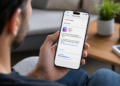 Pessoa segurando iPhone exibindo tela de download do iOS 27, a nova atualização anunciada na WWDC 2026.