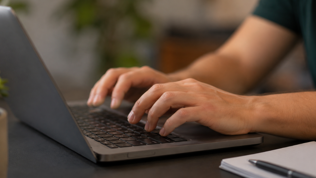 Mãos de candidato digitando em notebook durante inscrição no concurso TCE-MA 2026.
