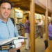 Estudante segura livros em uma biblioteca durante formação de pós-graduação.