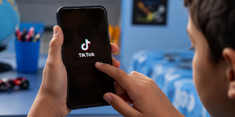 Criança acessa o TikTok pelo celular em contexto de proteção de dados de menores.