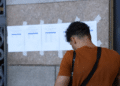 Candidato consulta lista de classificados em mural representando a nova chamada do CNU 2ª edição.