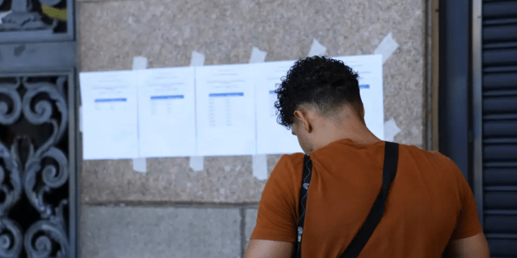Candidato consulta lista de classificados em mural representando a nova chamada do CNU 2ª edição.