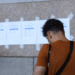 Candidato consulta lista de classificados em mural representando a nova chamada do CNU 2ª edição.