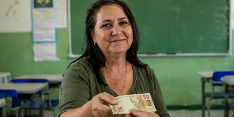 Professora da rede pública recebe pagamento em sala de aula, em referência ao trabalho no Enem 2026