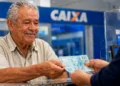 Idoso recebe dinheiro em agência bancária representando os pagamentos do INSS de agosto para beneficiários que recebem até um salário mínimo.