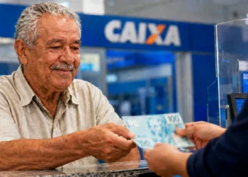 Idoso recebe dinheiro em agência bancária representando os pagamentos do INSS de agosto para beneficiários que recebem até um salário mínimo.