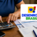 Arte com a marca do Desenrola Brasil sobre foto de pessoa usando calculadora diante de faturas e caderno com lista de contas a pagar, em referência aos descontos da renegociação
