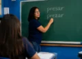 Professora escreve as palavras "presar" e "prezar" no quadro durante aula de língua portuguesa