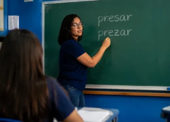 Professora escreve as palavras "presar" e "prezar" no quadro durante aula de língua portuguesa