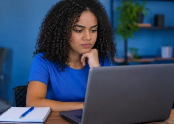 Jovem pesquisa oportunidades no notebook para conquistar o primeiro emprego na área de tecnologia.