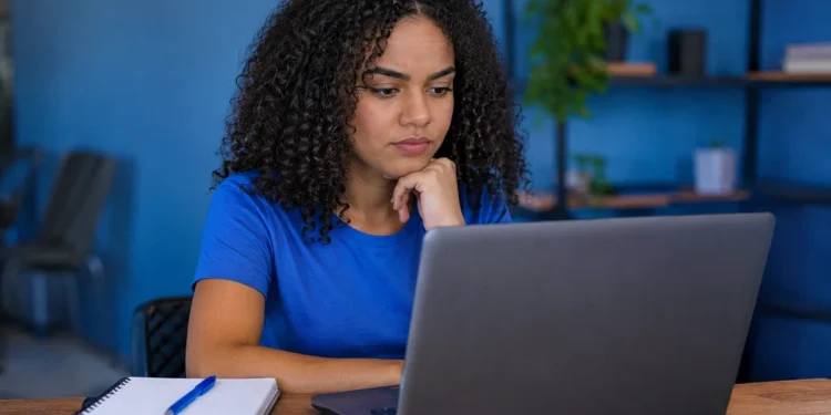Jovem pesquisa oportunidades no notebook para conquistar o primeiro emprego na área de tecnologia.