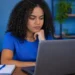 Jovem pesquisa oportunidades no notebook para conquistar o primeiro emprego na área de tecnologia.