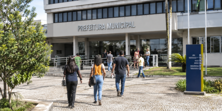 Pessoas caminham em direção a uma prefeitura, representando oportunidades de nível médio em seleções municipais de Minas Gerais.