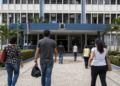 Pessoas caminham em direção a uma prefeitura, em referência aos processos seletivos com vagas de nível médio em Minas Gerais.