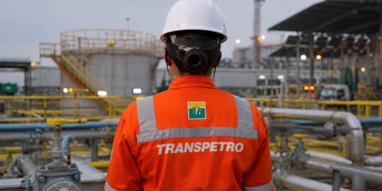 Trabalhador da Transpetro com uniforme de segurança em área industrial de petróleo e gás.
