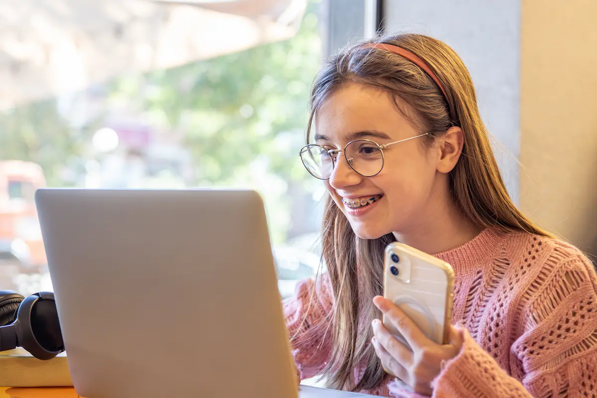 Estudante acessa computador e celular para consultar informações sobre cursos gratuitos do Pronatec.