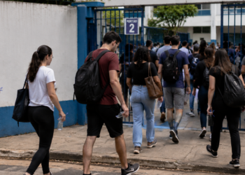 Candidatos chegam ao local de prova do processo seletivo do IBGE com mochilas e materiais para realização do exame.