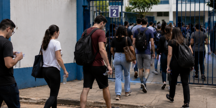Candidatos chegam ao local de prova do processo seletivo do IBGE com mochilas e materiais para realização do exame.