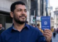 Trabalhador brasileiro segura carteira de trabalho em cenário urbano, representando a queda do desemprego para 5,3% no Brasil.