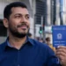 Trabalhador brasileiro segura carteira de trabalho em cenário urbano, representando a queda do desemprego para 5,3% no Brasil.