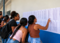 Candidatos consultam lista de convocação publicada em parede de instituição de ensino.