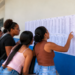 Candidatos consultam lista de convocação publicada em parede de instituição de ensino.