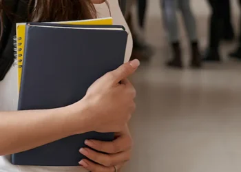 Estudante segura cadernos em ambiente escolar, representando a reaplicação do Encceja 2026 em outubro.