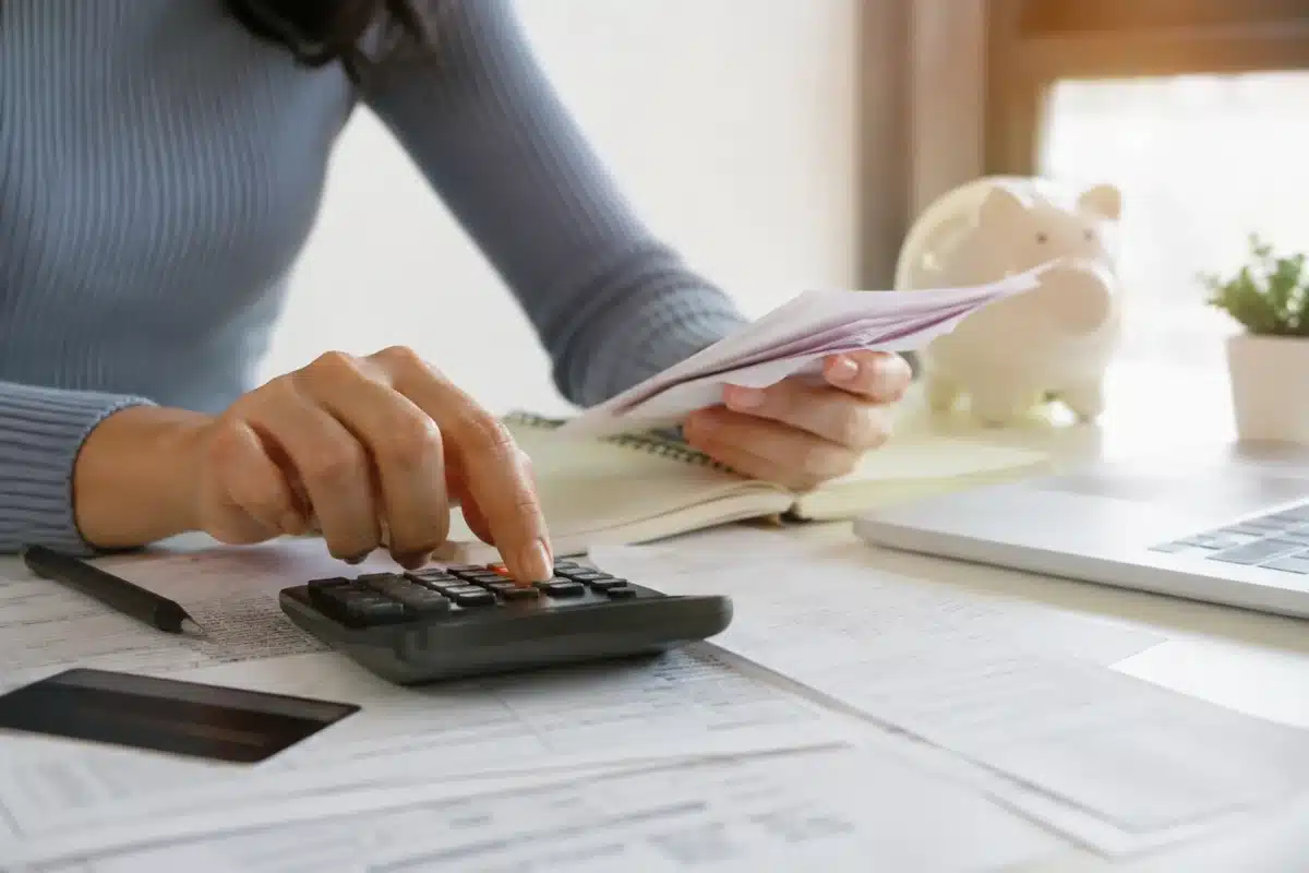Desenrola Adimplentes — Renegociação de dívidas de empréstimos pessoais Trabalhadora analisa contas e usa calculadora, representando as dívidas de empréstimos pessoais que podem ser renegociadas.