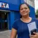 Mulher segura documentos em frente a uma agência da Caixa, representando a liberação do Saque Calamidade do FGTS em São Paulo.