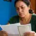 Mulher brasileira analisando documentos sobre benefício de aposentado falecido e orientações do INSS para familiares