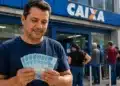 Homem segura notas de R$ 100 em frente a uma agência da Caixa, representando o saque do FGTS de R$ 6.220 a partir de 14 de agosto.