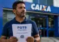 Trabalhador segura documento sobre FGTS em frente a uma agência da Caixa, representando ações judiciais para solicitar o saque do Fundo de Garantia.