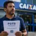 Trabalhador segura documento sobre FGTS em frente a uma agência da Caixa, representando ações judiciais para solicitar o saque do Fundo de Garantia.