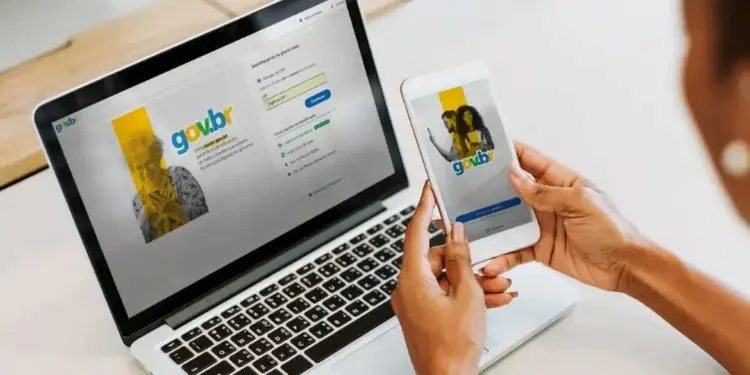 Segurança no acesso aos serviços do Gov.br Pessoa acessa o Gov.br pelo celular enquanto utiliza a plataforma em um notebook.
