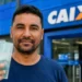 Homem segura dinheiro em frente a uma agência da Caixa representando o saque de R$ 6.220 do FGTS.