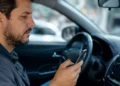 Motorista utiliza celular dentro do carro para realizar transferência de veículo de forma digital