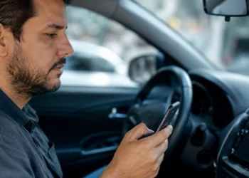 Motorista utiliza celular dentro do carro para realizar transferência de veículo de forma digital