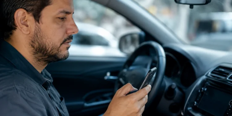 Motorista utiliza celular dentro do carro para realizar transferência de veículo de forma digital