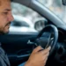 Motorista utiliza celular dentro do carro para realizar transferência de veículo de forma digital