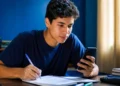 Estudante faz anotações enquanto usa o celular para treinar para o Enem pelo Gemini.