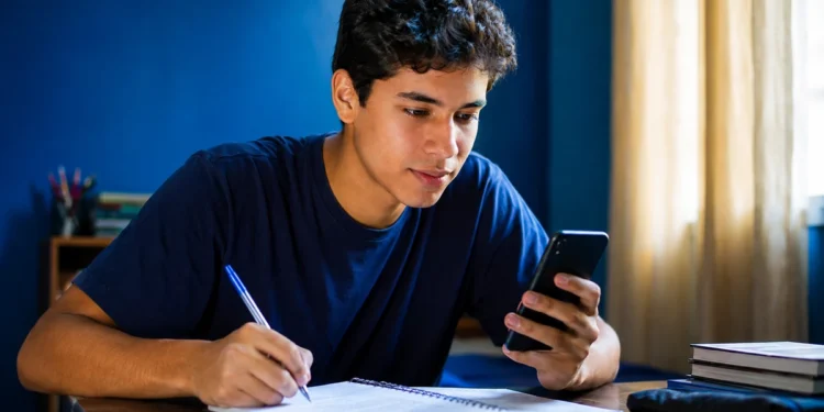 Estudante faz anotações enquanto usa o celular para treinar para o Enem pelo Gemini.