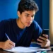 Estudante faz anotações enquanto usa o celular para treinar para o Enem pelo Gemini.