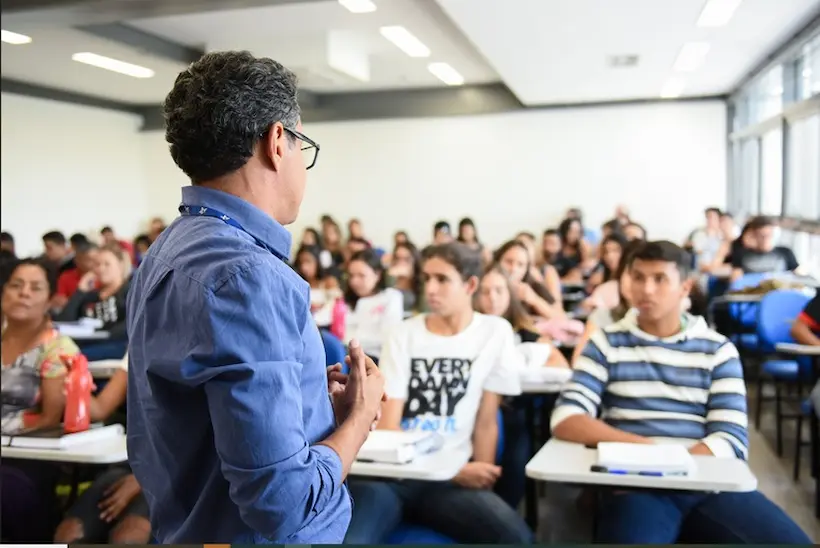 Professor em sala de aula com estudantes representando o processo de mudança de categoria acadêmica pelo MEC.